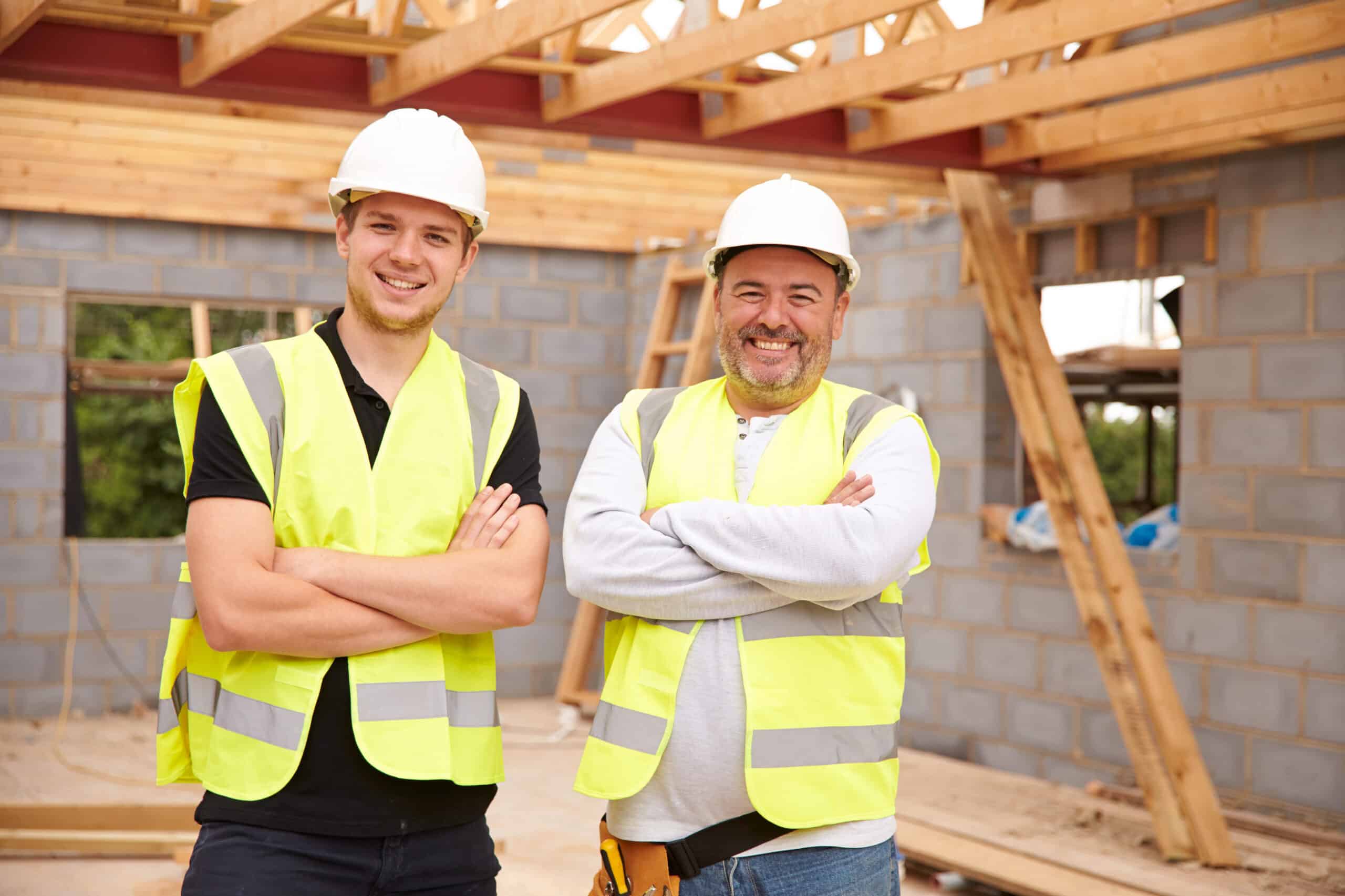 Portrait Of Carpenter With Apprentice Working On Site